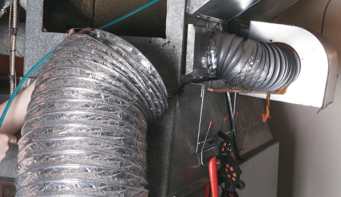 a professional cleaning an air duct