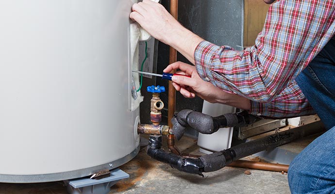 Person repairing water heater with screwdriver