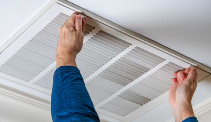 A person is removing vent cover on a ceiling