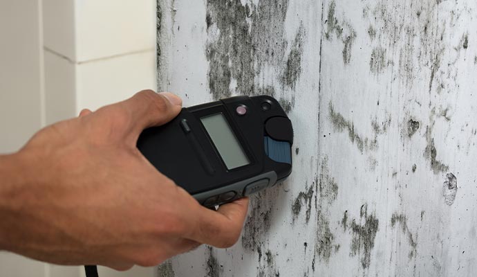 Person using a moisture meter to test the wall