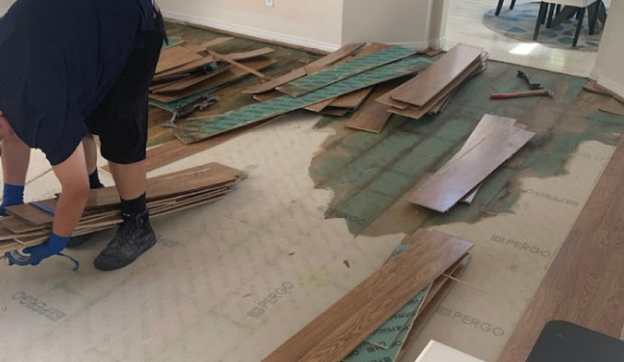 a person cleaning a wood floor that has been damaged by water.